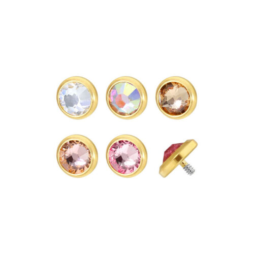 Cinque inserti per piercing in titanio dorato con cristalli chiari e colorati su sfondo bianco