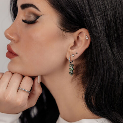 Donna con orecchini pendenti in argento e turchese africano su sfondo neutro