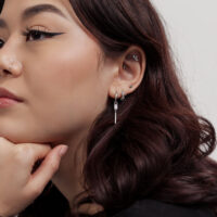 Donna con piccoli orecchini di cristallo quadrati su sfondo bianco