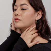 Donna con orecchini libellula neri e diversi piercing all'orecchio, profilo laterale