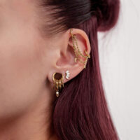 Catena Piercing Oro Luna & Stelle all'Orecchio Catena piercing dorata con luna e stelle su un orecchio con più anelli dorati