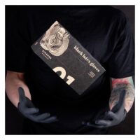 Persona con maglietta nera tiene una scatola di guanti in lattice Piranha neri su sfondo scuro