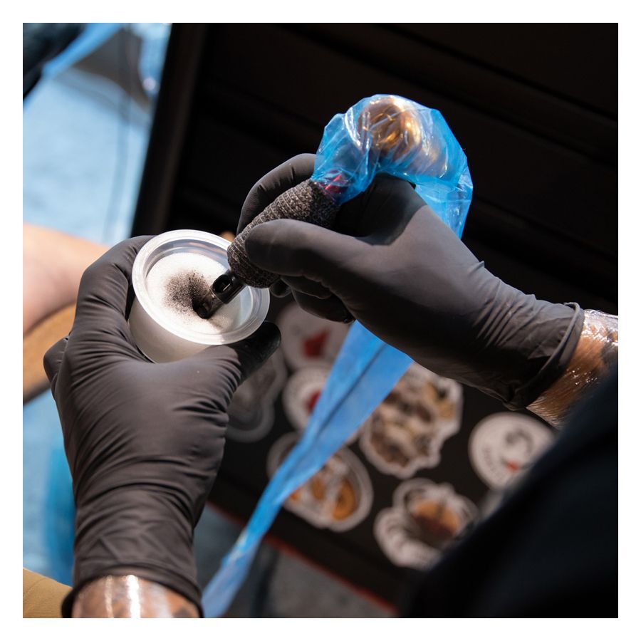 Guanti in lattice neri di Wildcat durante un tatuaggio con copertura blu