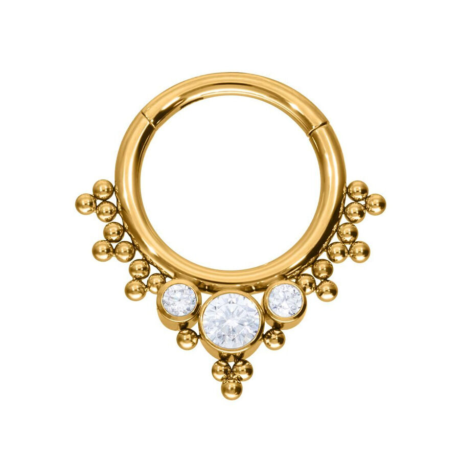 Anello piercing dorato con tre cristalli chiari su sfondo bianco