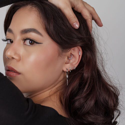 Donna con diversi piercing in argento e capelli acconciati, primo piano