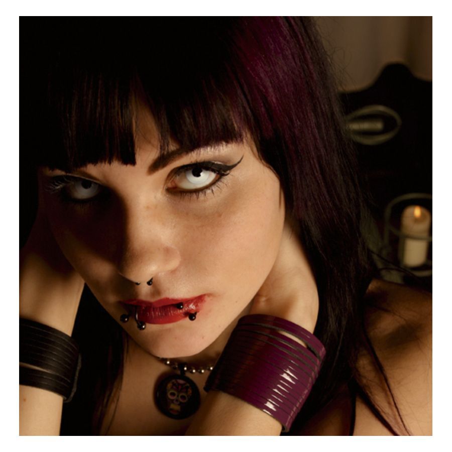 Donna con capelli scuri, indossa lenti a contatto White Only, candela sullo sfondo
