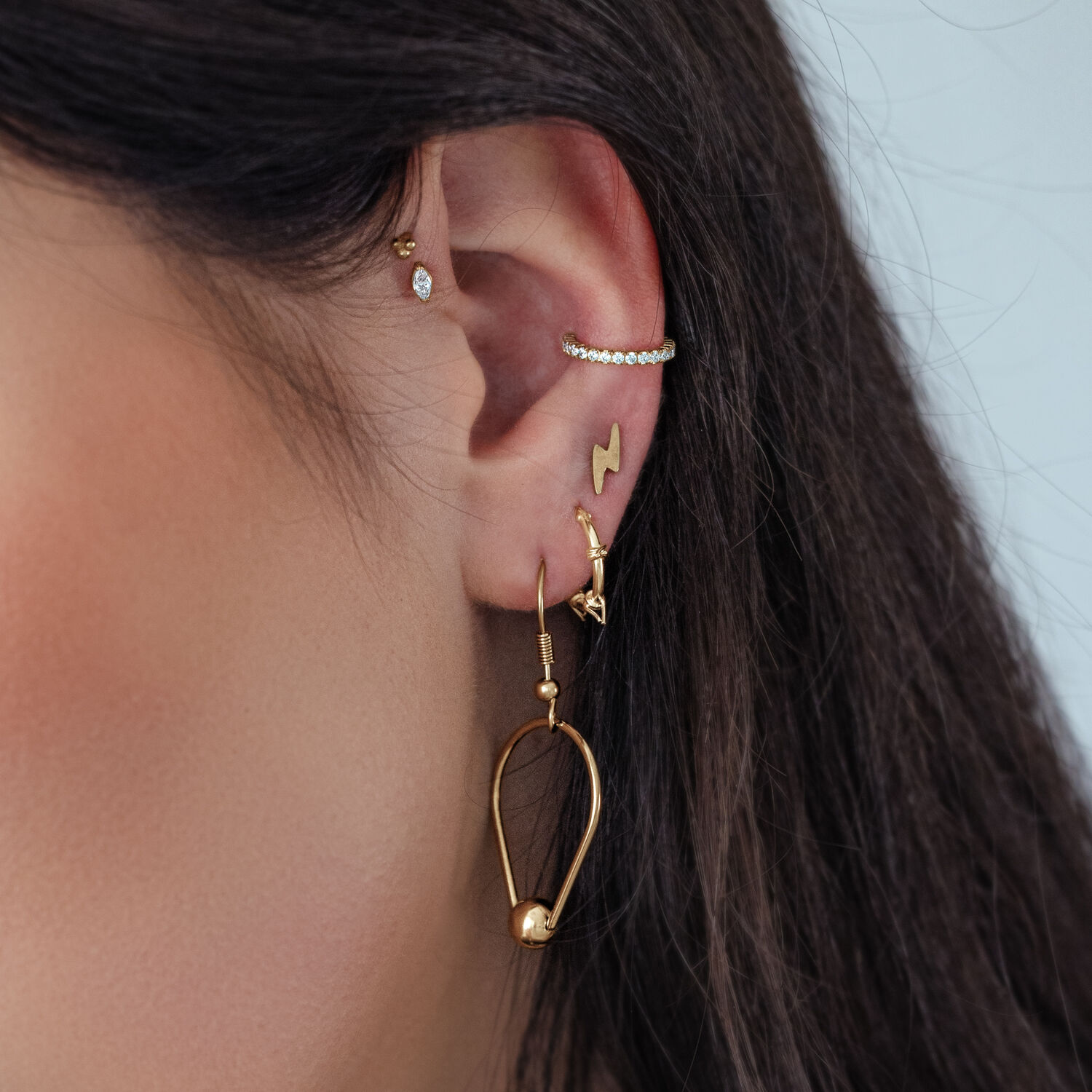 Inserto ovale in cristallo push fit dorato all'orecchio con altri piercing dorati