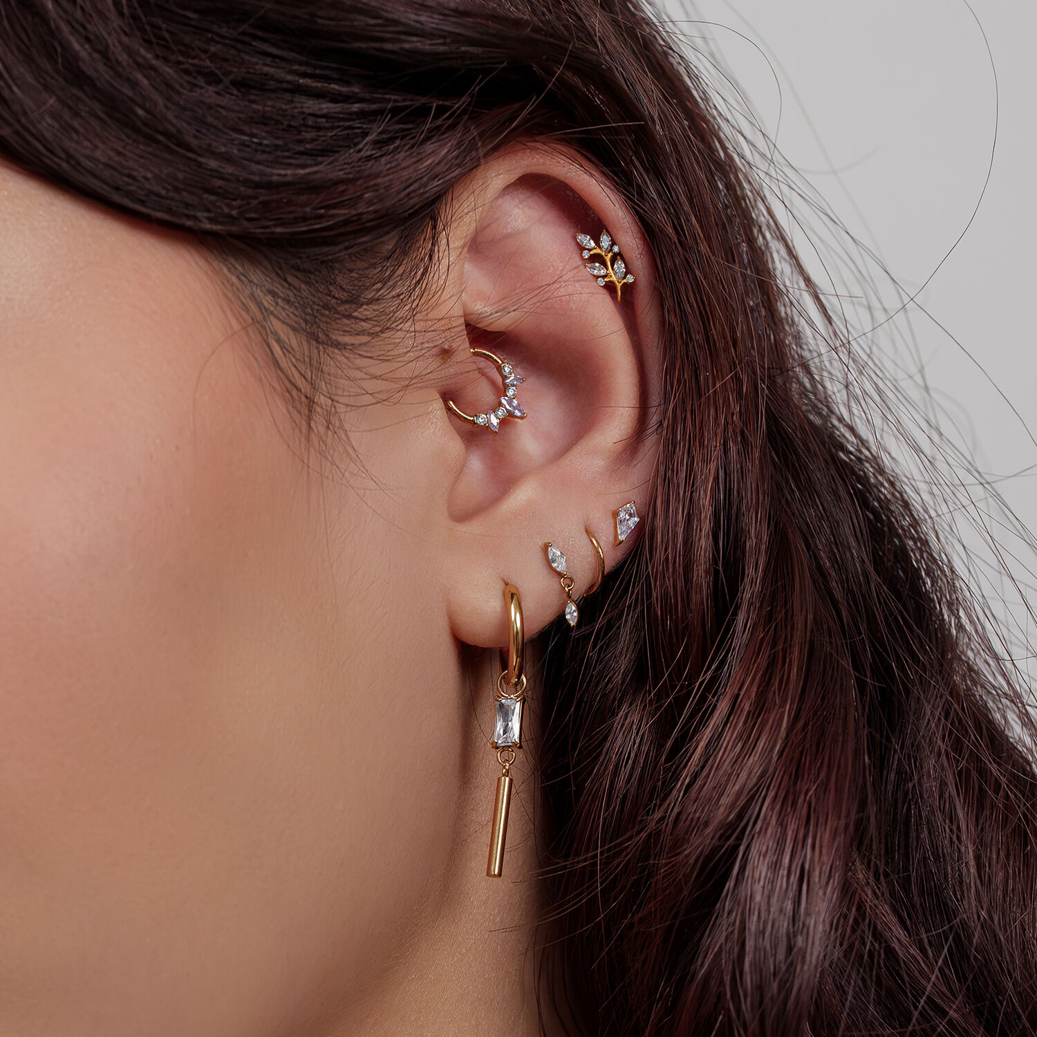 Attacco per piercing a foglia di cristallo dorato Orecchio con diversi piercing dorati, incluso un attacco a foglia di cristallo