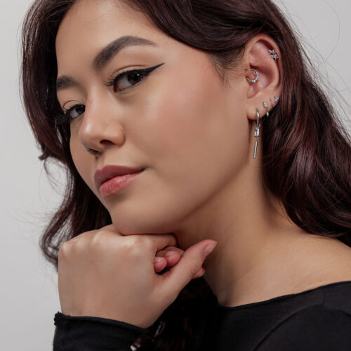 Donna con orecchini d'argento, inclusa una foglia di cristallo, su sfondo grigio