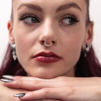 Donna indossa un Marquise Sunburst Septum Clicker dorato con pietre scintillanti