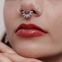 Primo piano di un clicker per setto in argento con cristalli in un naso, visibili labbra rosse