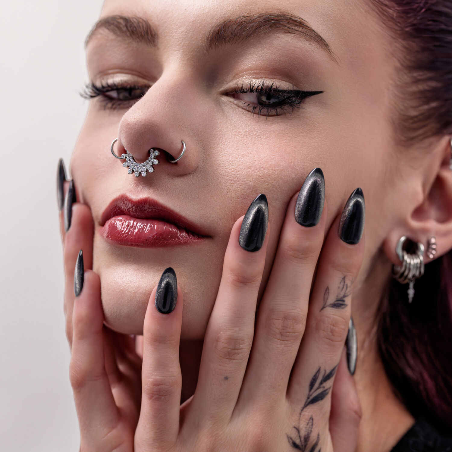 Primo piano di un clicker per setto nasale argento con cristalli su un modello femminile.