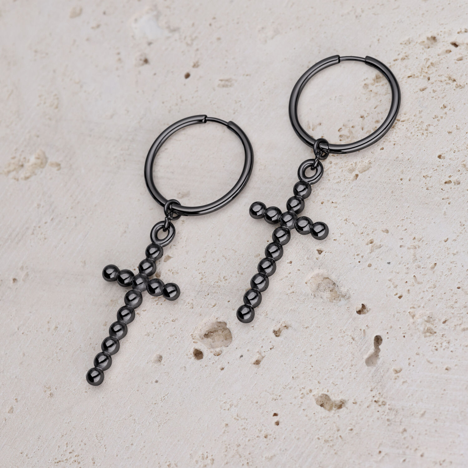 Due cerchi neri con ciondoli a croce di sfere su pietra chiara