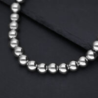 Primo piano di una collana in argento con sfere metalliche lucide su sfondo scuro