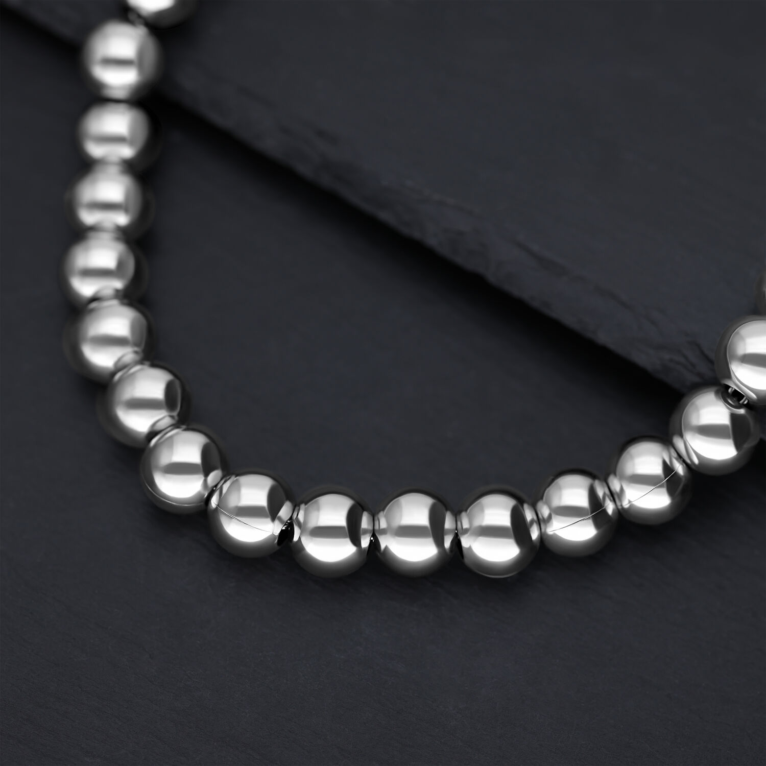 Primo piano di una collana in argento con sfere metalliche lucide su sfondo scuro