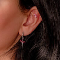 Accessorio auricolare argento con cristalli rossi a forma di baguette sull'orecchio di una persona