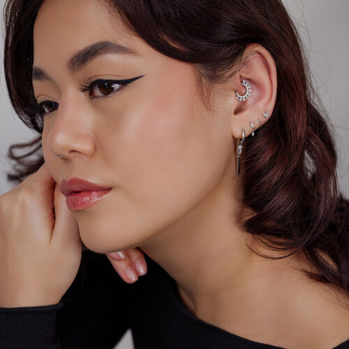 Donna con diversi orecchini e un clicker per setto nasale in argento con cristalli