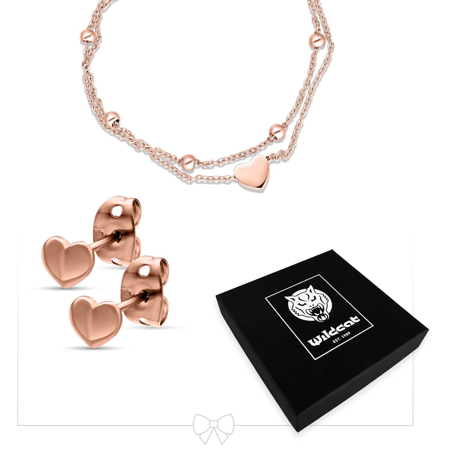 Bracciale in oro rosa con ciondolo a cuore e orecchini a cuore abbinati accanto a una scatola Wildcat nera su sfondo bianco