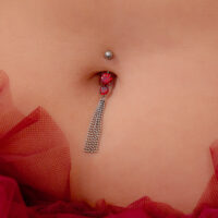 Banana bar in argento con cristalli rossi e catene, indossata in un ombelico.