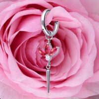 Orecchino d'argento con cristalli rossi, a forma di fiore, davanti a una rosa rosa