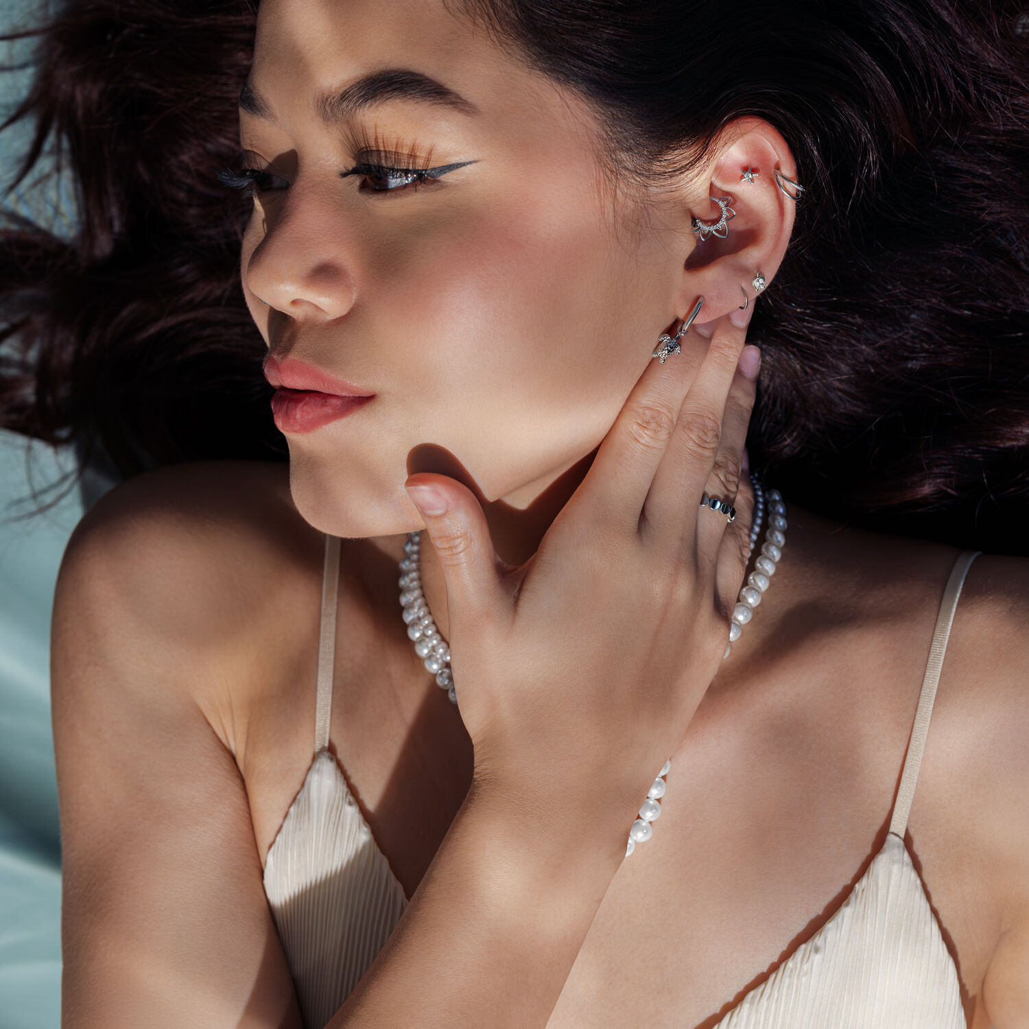 Donna con orecchini d'argento e collana di perle, di lato alla luce