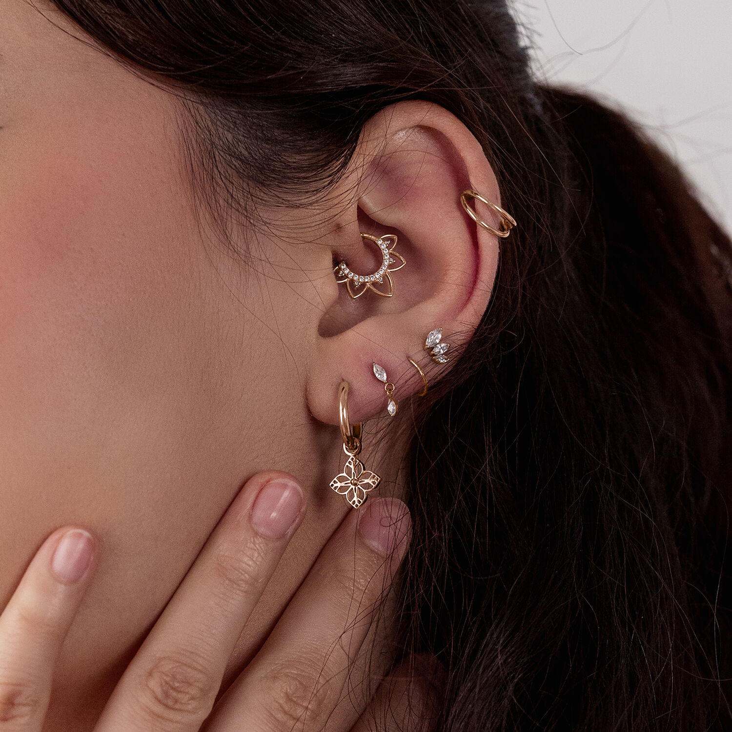 Donna con diversi orecchini in oro rosa, incluso un design ornamentale floreale