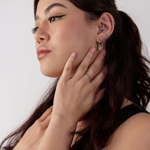 Donna con diversi orecchini d'argento, decorati con motivi floreali, profilo laterale