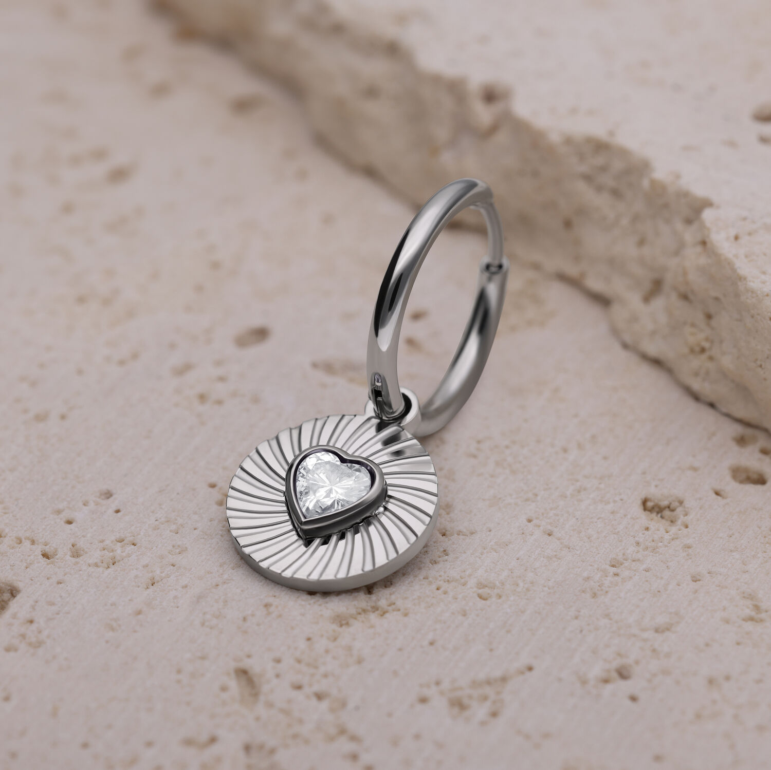 Orecchino d'argento con ciondolo a forma di cuore su pietra chiara