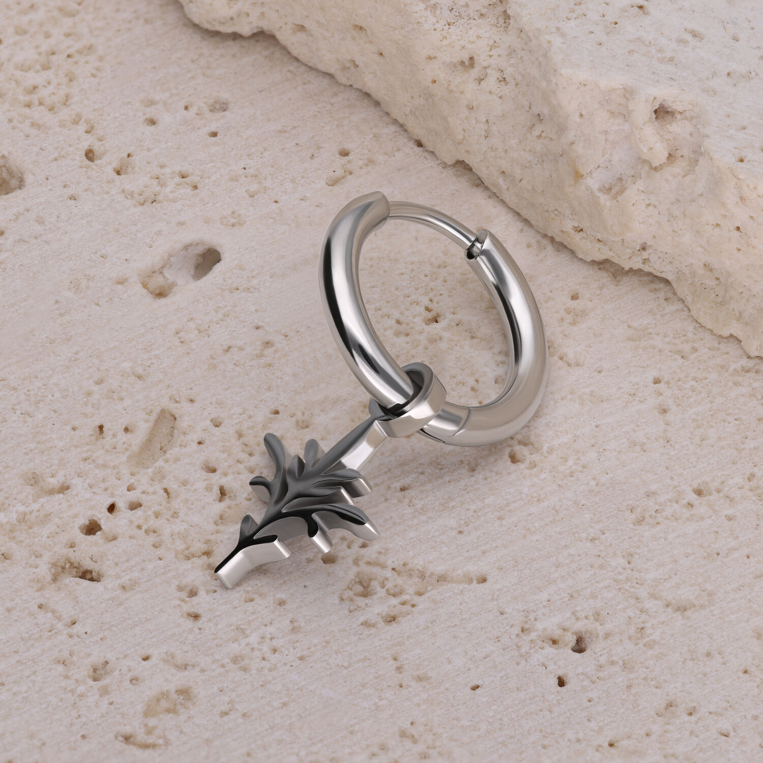 Orecchino a cerchio d'argento con ciondolo nero a forma di ramo su pietra chiara