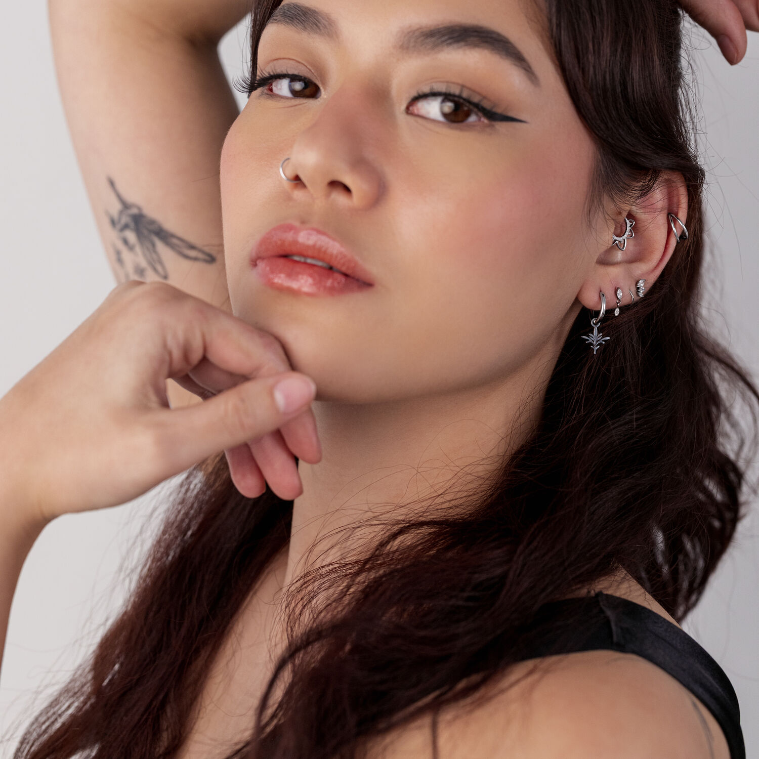 Donna con capelli lunghi indossa Mini Branch orecchini in acciaio chirurgico, con più piercing e tatuaggi visibili.