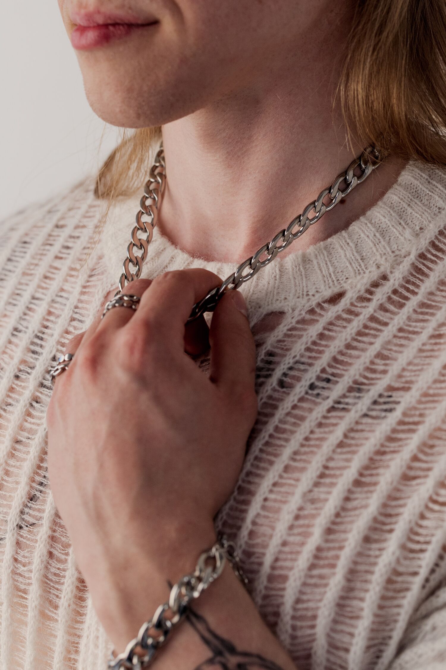 Persona con collana Chunky argento e maglione bianco a maglia
