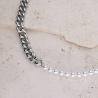 Collana a maglie d'argento combinata con perle sintetiche su sfondo di pietra chiara