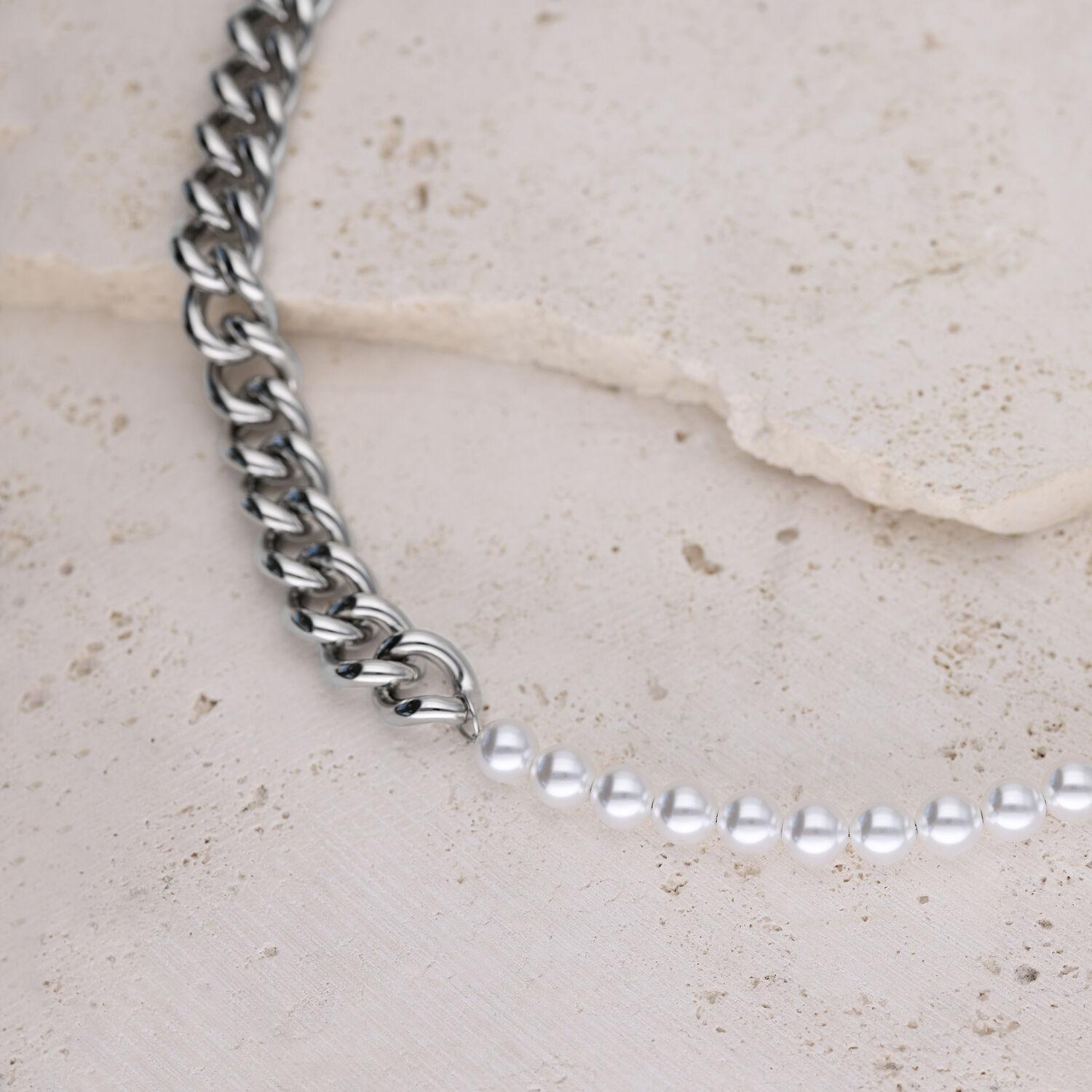 Collana a maglie d'argento combinata con perle sintetiche su sfondo di pietra chiara