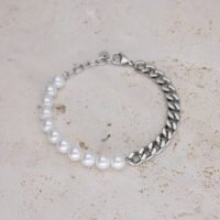 Bracciale con perle bianche e catena argentata su pietra chiara