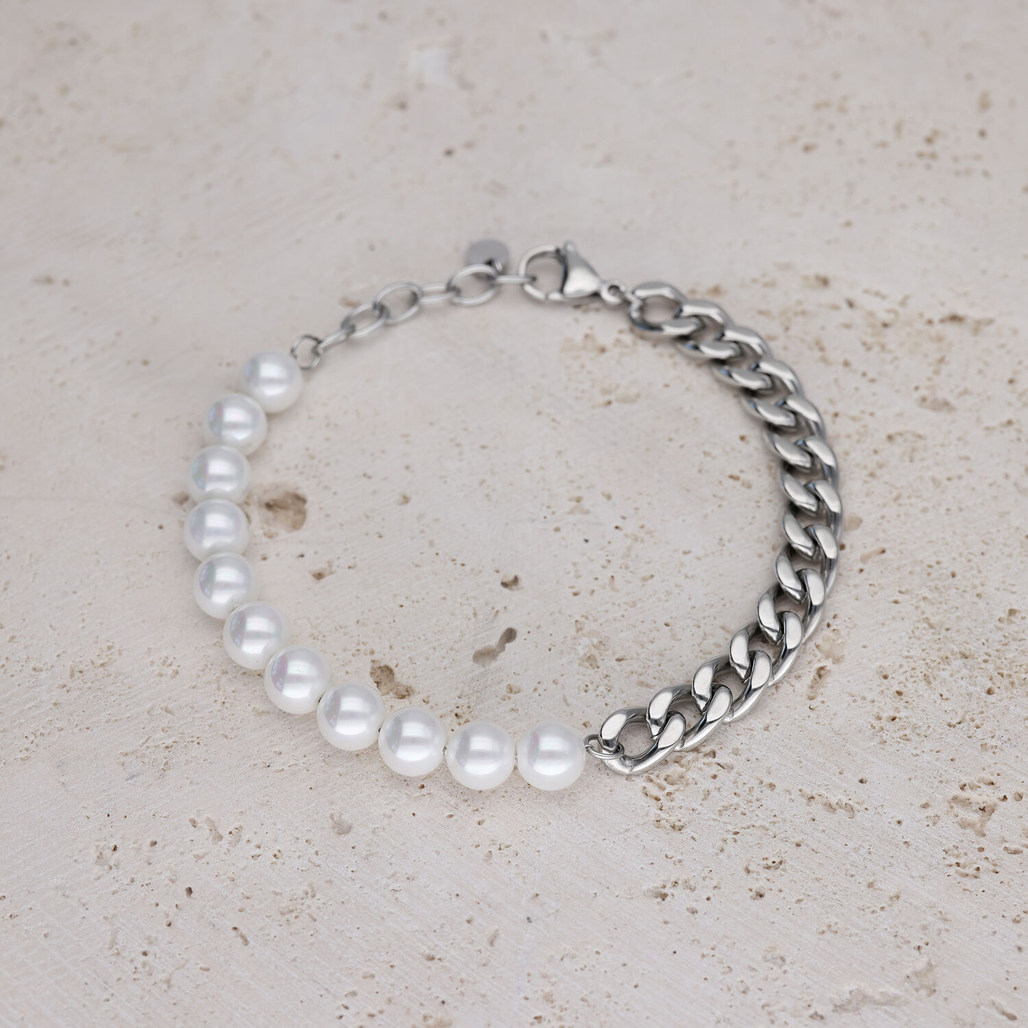Bracciale con perle bianche e catena argentata su pietra chiara
