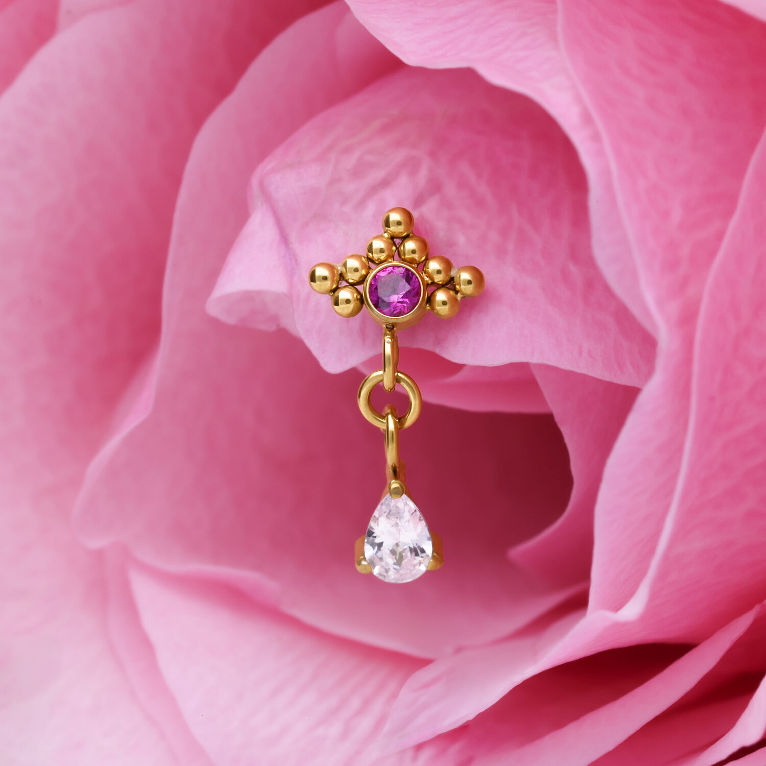 Punta per piercing dorata con cristallo rosso e pendente a goccia su petalo rosa