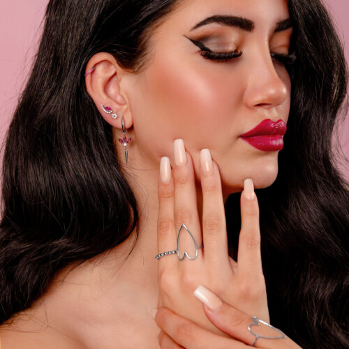 Donna con orecchini d'argento e cristallo rosso su sfondo rosa