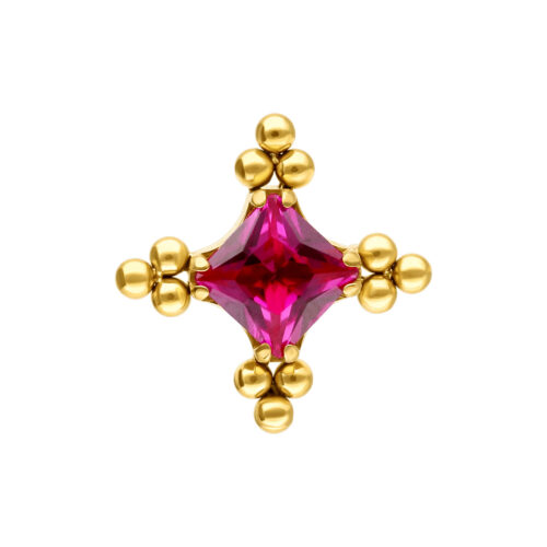 Inserto dorato con cristallo rosso al centro e piccole sfere dorate ai bordi, su sfondo bianco