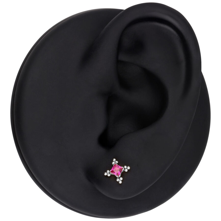 Modello di orecchio con accessorio per piercing in argento e cristallo rosso su sfondo nero