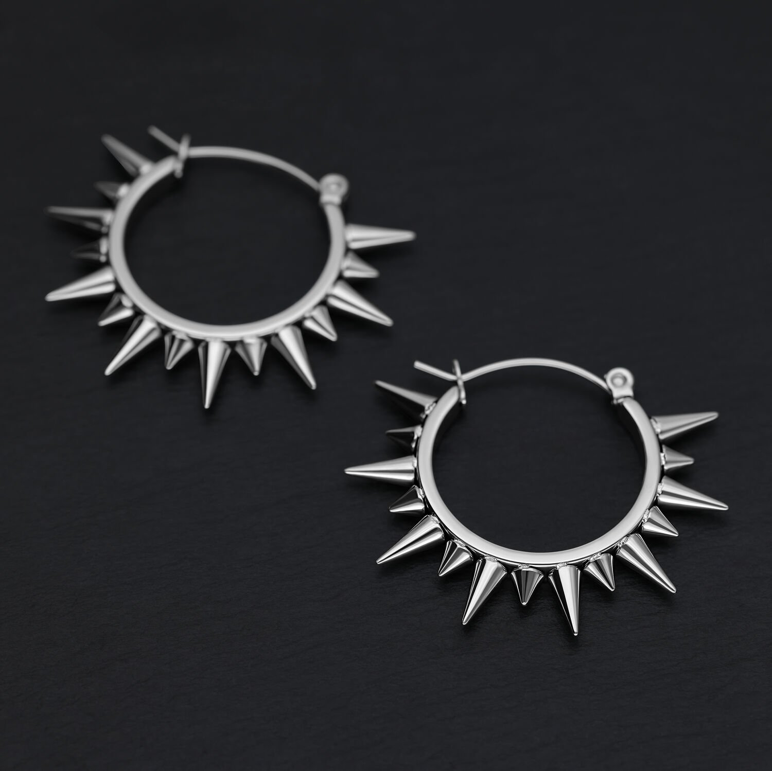 Due orecchini a spillo argentati in acciaio chirurgico su sfondo nero