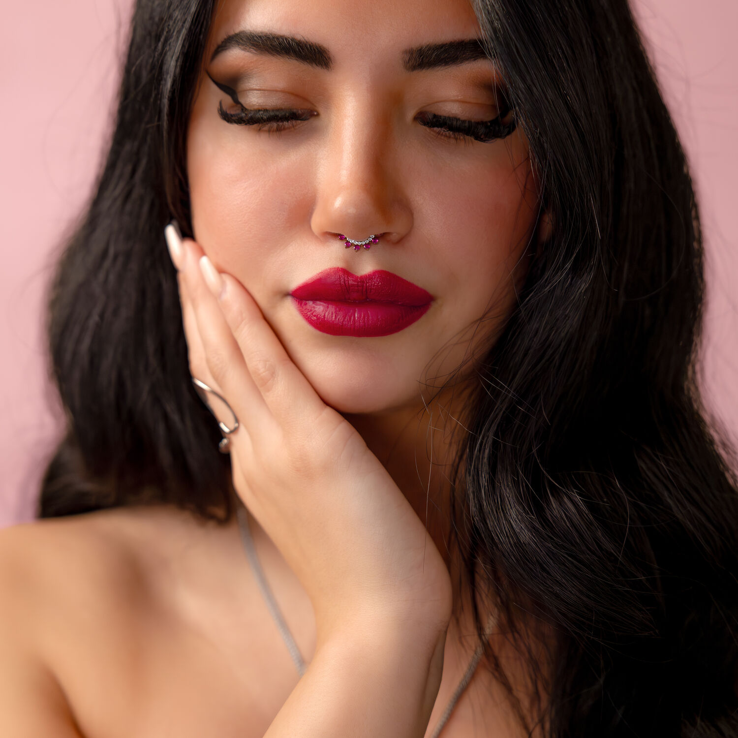 Donna con occhi chiusi, indossa Ruby Red Clicker Piercing con cristallo rosso, sfondo rosa