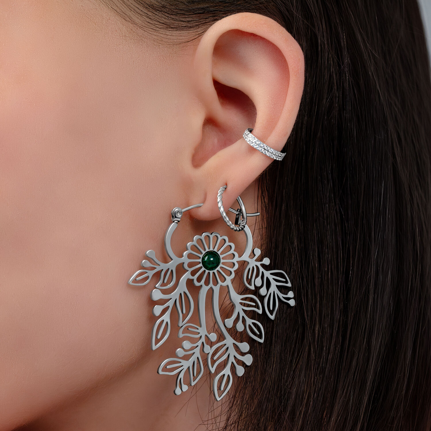 Primo piano di un orecchio con orecchino pendente in argento a forma di fiore e piccolo perno