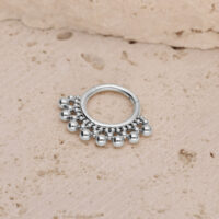 Clicker per setto in titanio argento con sfere Clicker per setto argento con piccole sfere su sfondo di pietra strutturata