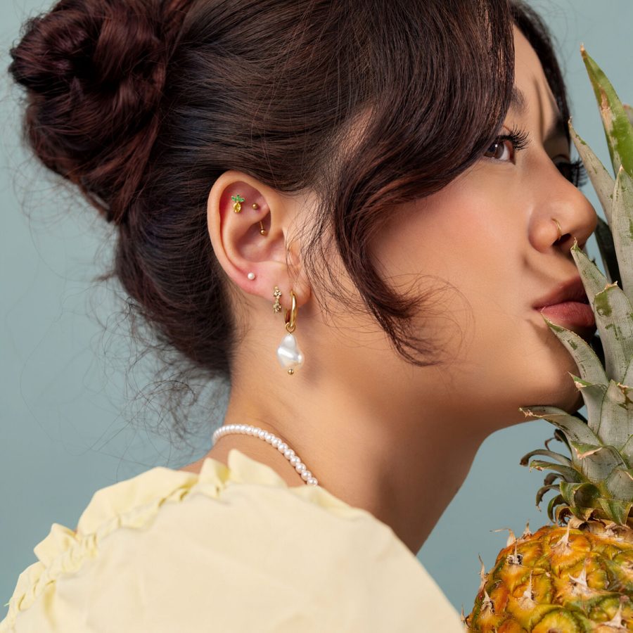 Donna con orecchini dorati e un attacco a forma di ananas, profilo laterale