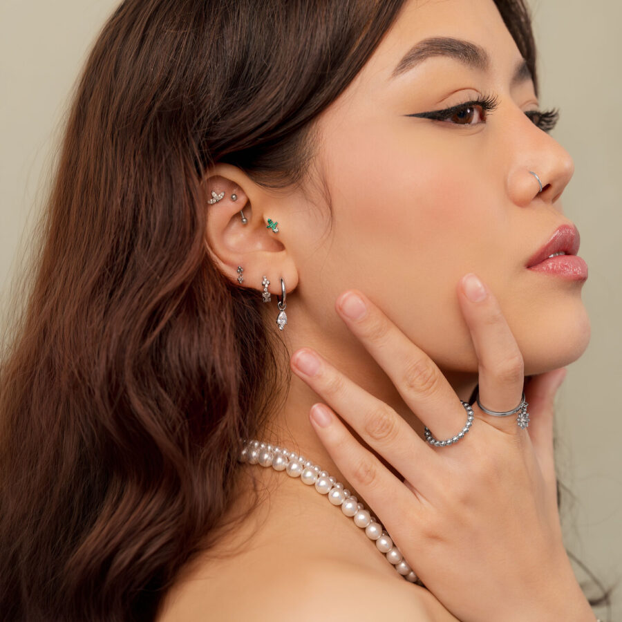 Donna con diversi piercing in argento, incluso Cactus Push Fit, fotografata di lato