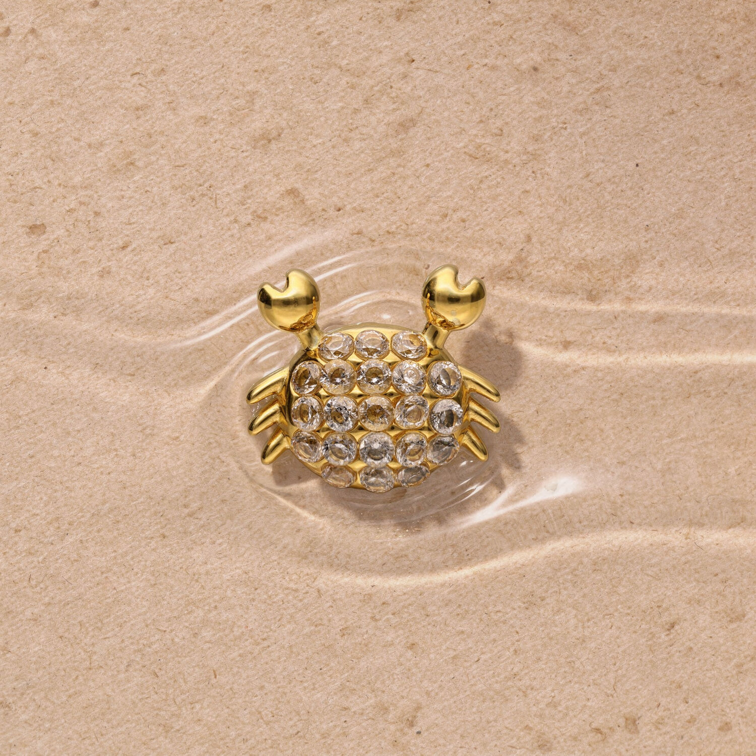 Inserto a pressione dorato a forma di granchio Inserto dorato a forma di granchio con strass su sfondo sabbioso