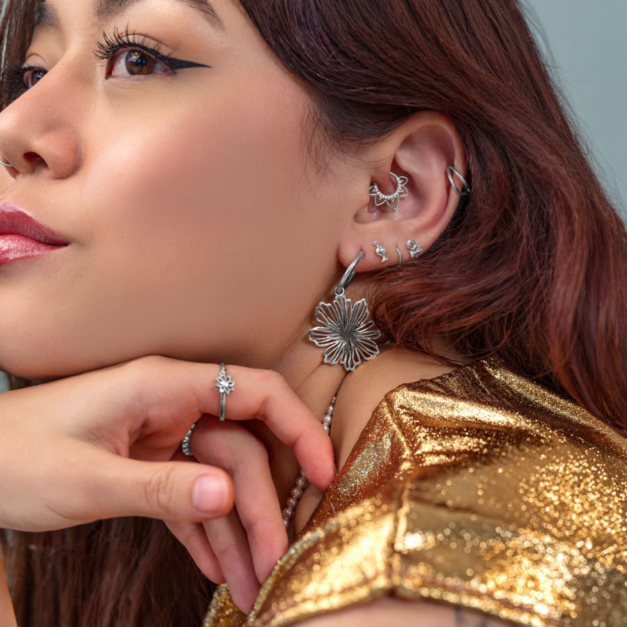 Donna con diversi orecchini e piercing d'argento, abbigliamento dorato