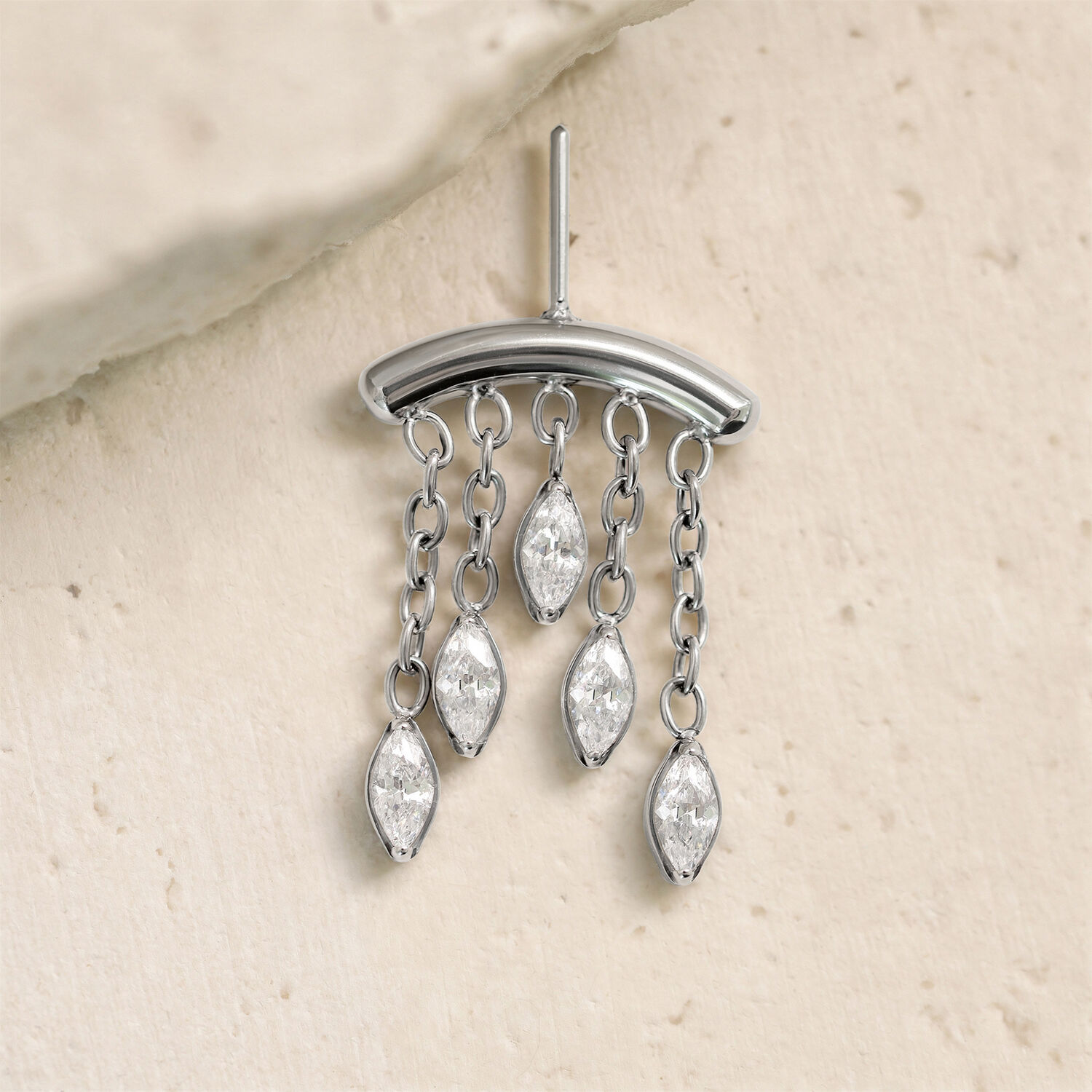 Accessorio argento con cinque gocce cristalline su catene su sfondo chiaro