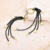 Orecchini Pendenti Mystic Night Oro/Nero Orecchini neri e dorati con ciondoli a forma di stella e luna su sfondo beige