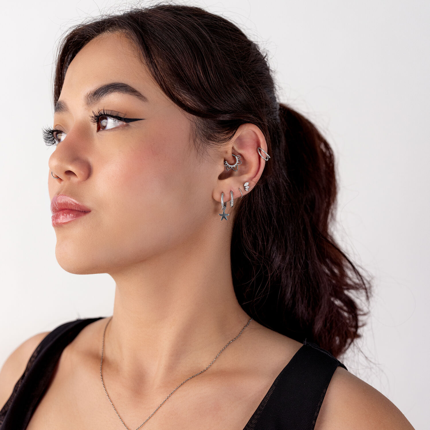 Donna con diversi piercing all'orecchio in argento, profilo laterale